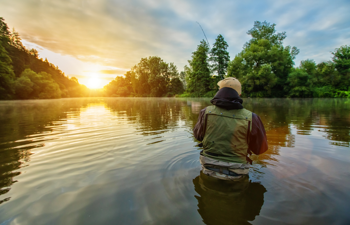 Angler fishing a calm lake at sunrise